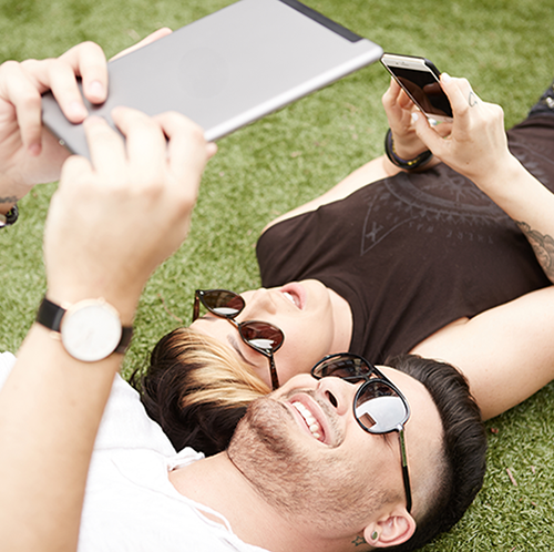 Two men review Pivot Point Lab on their tablet device whilst lying on the grass